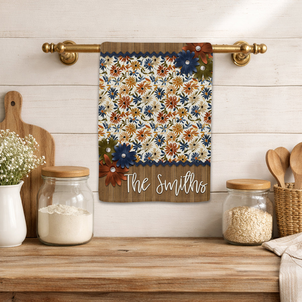 Personalized fall kitchen towel featuring navy, rust, golden yellow, and olive floral patterns with layered flower accents, navy trim, and a rustic wood-look family name panel.