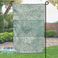 Decorative garden flag with 'Welcome The Smiths' text and floral patterns in a garden setting.