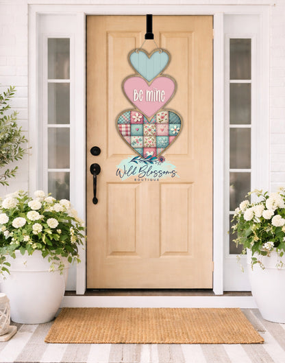 Decorative heart-shaped door hanger on a wooden door with flowers on either side.